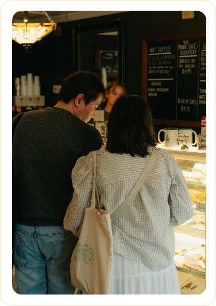 Sarah and Ji browsing pastries together at a cafe counter