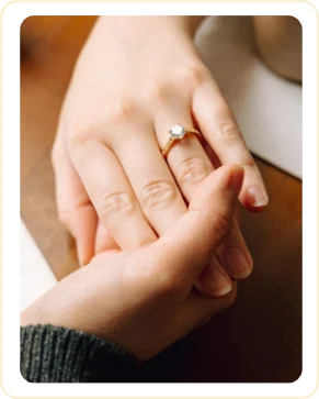 Close-up of Sarah's hand with her engagement ring resting on Ji's hand